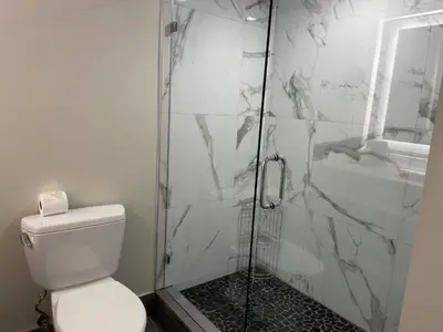 a bathroom with a toilet and a glass shower at Hi View Inn & Suites in Manhattan Beach