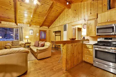 a large kitchen with wooden walls and wooden flooring at Pine Cone Cottage by Big Bear Vacations Adorable Walk To Lake Furnished Chalet in Big Bear Lake