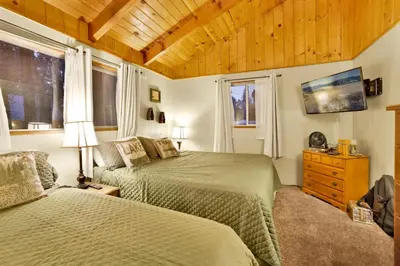 a bedroom with two beds and a wooden ceiling at Pine Cone Cottage by Big Bear Vacations Adorable Walk To Lake Furnished Chalet in Big Bear Lake