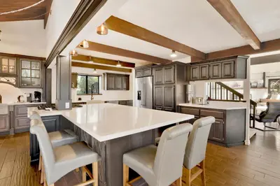 a kitchen with a large island with white counter chairs at Soaring Pines by Big Bear Vacations Central Cozy Estate Chalet in Big Bear Lake
