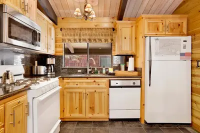 a kitchen with wooden cabinets and a white refrigerator at Smith Chalet at Snow Summit- Furnished Resort Condo- Foosball- Walk To Lifts in Big Bear Lake