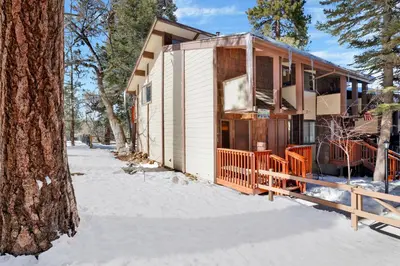 a house in the snow next to a tree at Smith Chalet at Snow Summit- Furnished Resort Condo- Foosball- Walk To Lifts in Big Bear Lake