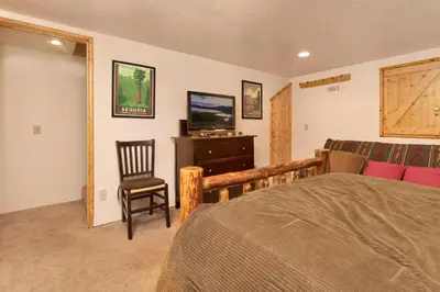 a bedroom with a bed and a chair and a television at Swiss Delight by Big Bear Vacations Hot Tub Game Tables Central in Big Bear Lake