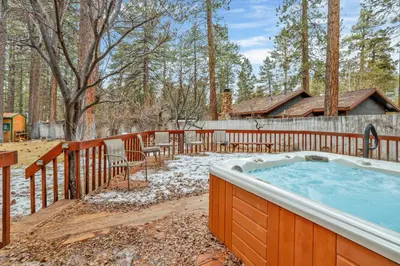 a hot tub in a yard with a fence at Fawnskin Log Cabin- Luxurious Group Log Cabin Estate- Hot Tub- Walk to Lake in Fawnskin
