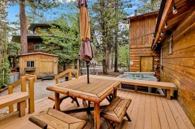 a wooden table with an umbrella on a deck at The Lost Compass- Hot Tub- Games- Walk To Lake or Marina in Big Bear Lake