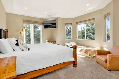 a bedroom with a large bed and a chair at Sunset Ridge Villa- Incredible Log Cabin Estate- Hot Tub- Game Tables- in Big Bear Lake