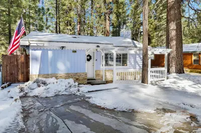a white house with a flag in the snow at Cozy Summit- Cozy Central Resort Chalet- Minutes to Activities in Big Bear Lake