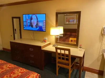 a hotel room with a television and a desk with a mirror at New Century Inn in San Gabriel