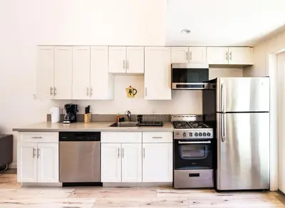 a kitchen with white cabinets and a stainless steel refrigerator at Chic 1-Bed Hollywood Loft Iconic Sign Views & Private Parking in Los Angeles