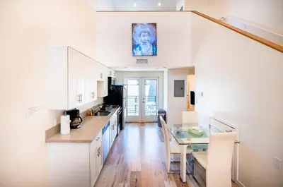 a kitchen with white cabinets and a glass table at Chic 1-Bed Hollywood Loft Iconic Sign Views & Private Parking in Los Angeles
