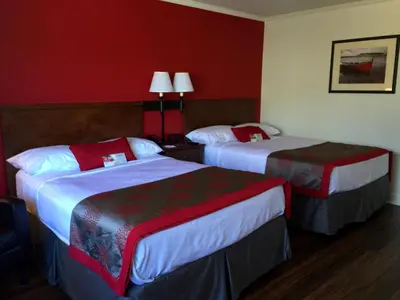 two beds in a hotel room with red walls at Ramada by Wyndham Torrance in Torrance