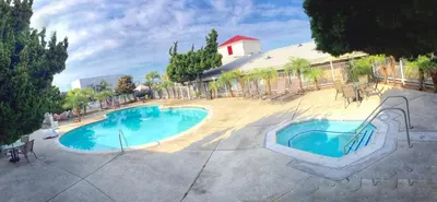 a swimming pool in a courtyard with chairs and a building at Ramada by Wyndham Torrance in Torrance