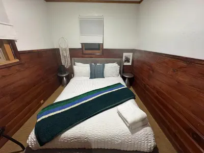 a large bed in a room with wooden walls at Three Pines Cabins in Big Bear Lake
