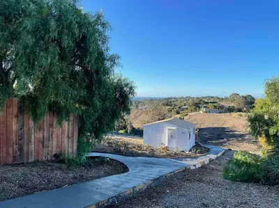 a small white building on a sidewalk next to a fence at 30 PCT OFF! Malibu Serene Cabin, Ocean View, Beach in Malibu