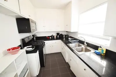 a kitchen with white cabinets and a black counter top at Hollywood Business Apartments in Los Angeles