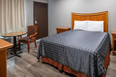 a hotel room with a bed and a table and chair at Starlite Motel in San Bernardino