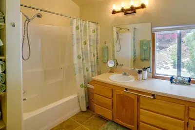 a bathroom with a tub shower and a sink at Peaceful Pines Running Springs Home with 3 Decks in Running Springs