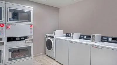 a laundry room with washing machines and a tv at Suites Los Angeles CA Los Angeles LAX in Inglewood
