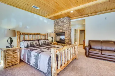 a bedroom with a large bed and a leather couch at Elegant Big Bear Cabin Half Mi to Big Bear Lake! in Big Bear Lake