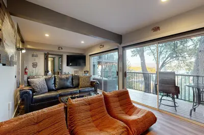 a living room with a couch and a balcony at Surreal Feel Lakeview Chalet in Lake Arrowhead