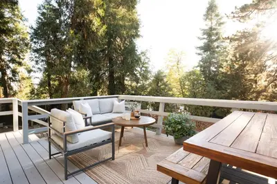 a patio with a couch and a table on a deck at Wild Olive Lodge ° Serene grandma chíc getaway cabin in Running Springs