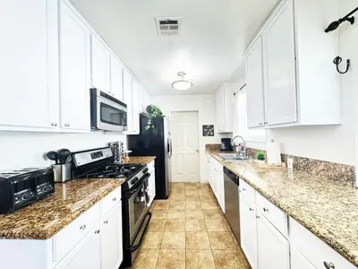 a kitchen with white cabinets and a black refrigerator at Charming 3BR House - Hal-UC in Los Angeles