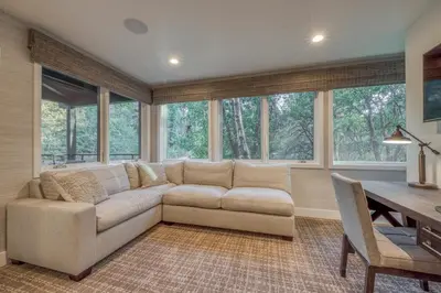 a living room with a couch and a table and windows at Lake Front Modern Luxury in Lake Arrowhead