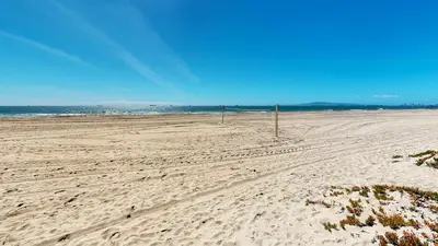 an empty beach with a volleyball net in the sand at 3 Bedroom 2 Bath Beachfront Home in Huntington Beach
