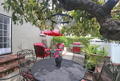 a patio with a table and chairs under a tree at Charming Pasadena English Cottage on Tree Lined Street in Pasadena