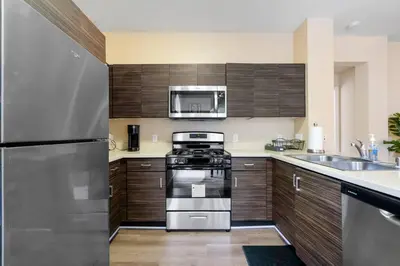 a kitchen with stainless steel appliances and wooden cabinets at Lovely & coxy 2BR/2BA! 5MIN to Disney! in Anaheim