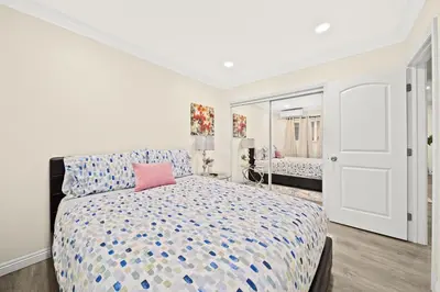 a white bedroom with a bed with a pink pillow at Cozy & Serene ~ 12mins to Downtown LA in Alhambra