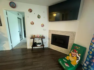 a living room with a fireplace and a green chair at Mario, Disney & not themed Loft Universal Studios 10min loft apartment in Los Angeles