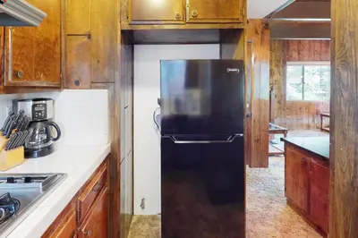 a black refrigerator in a kitchen with wooden cabinets at Rocky Pines in Twin Peaks