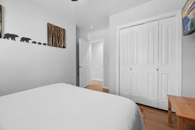 a white bedroom with a bed and a table at 3 Cubs Lakefront - Stunning lakeside home with Hot Tub, Foosball, and Lake View in Big Bear Lake
