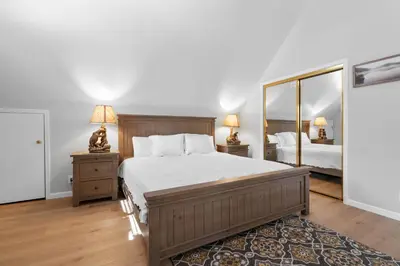 a bedroom with a bed and two lamps and a mirror at 3 Cubs Lakefront - Stunning lakeside home with Hot Tub, Foosball, and Lake View in Big Bear Lake