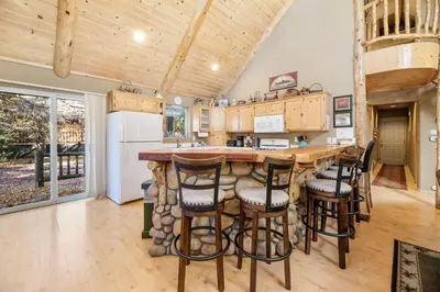 a kitchen with a large wooden bar with stools at Abe's Cool Cabin - Nice luxury home with a game room, hot tub, and pool table in Big Bear Lake