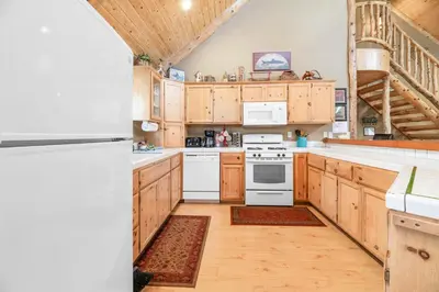 a kitchen with white appliances and wooden cabinets at Abe's Cool Cabin - Nice luxury home with a game room, hot tub, and pool table in Big Bear Lake