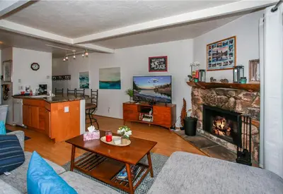 a living room with a fireplace and a table at Bayview Condo - Condo is cozy and a great location for kayaking and paddle boarding! in Big Bear Lake