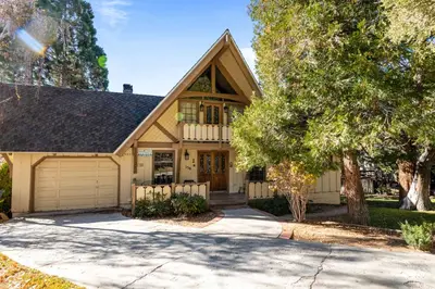 a house with a garage and a tree at Alpine Lakefront - Lakefront cabin and all the amenities really fun from the pool table and spa in Big Bear Lake