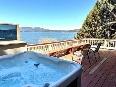 a hot tub on a deck with a view of the water at Alpine Lakefront - Lakefront cabin and all the amenities really fun from the pool table and spa in Big Bear Lake