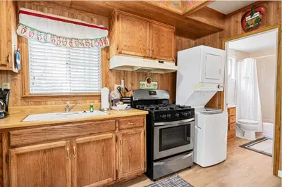 a kitchen with wooden cabinets and a stove and refrigerator at Apples Delight -WALK TO THE LAKE! Enjoy the huge backyard with lovely forest views ! in Big Bear Lake
