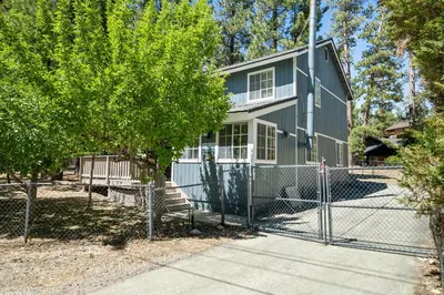 a house with a fence in front of it at Apples Delight -WALK TO THE LAKE! Enjoy the huge backyard with lovely forest views ! in Big Bear Lake
