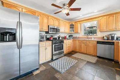 a kitchen with wooden cabinets and a stainless steel refrigerator at BB Lake View Lodge - Gorgeous Lakeviews, Hot Tub, Jetted Tub, and Firepit! in Big Bear Lake