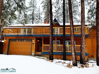a large wooden house with a garage in the snow at Bear Claw Cabin - Perfect location with an amazing game room and hot tub! in Big Bear Lake