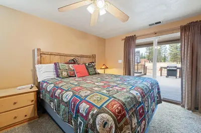 a bedroom with a bed and a sliding glass door at Bear Family Cabin - Stay together & play together! Foosball, billiards, hot tub, walk to lake! in Big Bear Lake