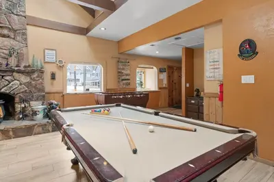 a pool table in a room with a fireplace at Bear Family Cabin - Stay together & play together! Foosball, billiards, hot tub, walk to lake! in Big Bear Lake