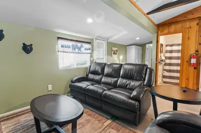 a living room with a leather couch and a table at Bear Paw Cabin - Cozy and quaint, the perfect mountain getaway! in Big Bear Lake