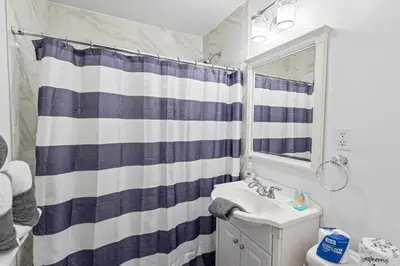 a bathroom with a blue and white shower curtain and a sink at Bear Paw Cabin - Cozy and quaint, the perfect mountain getaway! in Big Bear Lake