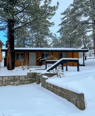 a log cabin in the snow with a snow covered yard at Bear Paw Cabin - Cozy and quaint, the perfect mountain getaway! in Big Bear Lake