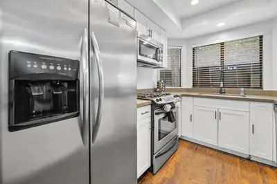 a kitchen with stainless steel appliances and white cabinets at Bear Retreat - Modern location within walking distance to Snow Summit with a private hot tub! in Big Bear Lake